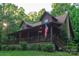 Log cabin home with a covered front porch, lush landscaping, steps, and an American flag at 95 Odell Ct, Taylorsville, NC 28681