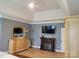 Main bedroom with tray ceiling, fire place, and view into walk-in closet at 103 Doyle Farm Ln, Mooresville, NC 28115