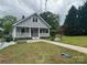 Quaint two-story home with a charming covered porch, spacious lawn, and mature trees at 103 Duke St, Great Falls, SC 29055