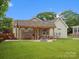 Inviting covered backyard patio with outdoor dining area, fire pit, and swing for relaxing and entertaining at 107 Pressley St, Clover, SC 29710
