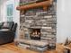Close up of stone fireplace with lit logs, wooden mantel, and hardwood floors at 107 Pressley St, Clover, SC 29710