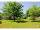 Spacious backyard with mature trees, manicured lawn, and a classic wooden picket fence at 1110 Archer Farm Dr, Salisbury, NC 28144