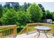 Outdoor deck with a round glass table and stairs surrounded by a lush green backyard and trees at 1110 Archer Farm Dr, Salisbury, NC 28144