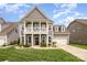 Two-story home featuring a charming front porch, well-manicured lawn, and lush landscaping at 1111 Thessallian Ln, Indian Trail, NC 28079