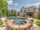 Spacious backyard featuring a pool, spa, outdoor kitchen, and covered patio for entertaining at 1404 Lookout Cir, Waxhaw, NC 28173