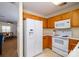 A corner view of the kitchen with white appliances, wooden cabinets, and adjacent living space at 15042 Deshler Ct, Charlotte, NC 28273