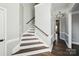 Elegant staircase featuring hardwood steps, white risers, and a dark wood railing at 17101 Windy Oaks Ct, Cornelius, NC 28031
