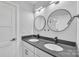 Bathroom featuring a double vanity with matte fixtures, round mirrors, and gray countertops at 1933 St Mark St, Charlotte, NC 28216