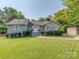 Charming single-story home with manicured lawn, complemented by lush greenery, and a welcoming entrance at 214 Wilcrest Dr, Matthews, NC 28105