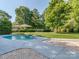 Lush backyard with a sparkling in-ground pool, stone accents, and mature landscaping at 214 Wilcrest Dr, Matthews, NC 28105