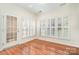 Bright office space with hardwood floors, shuttered windows, and a glass door, offering a versatile workspace at 243 Lincoln St, Charlotte, NC 28203