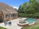 Lush backyard with freeform pool, spa, patio, chairs, and partial view of house at 310 E Waterlynn Rd, Mooresville, NC 28115
