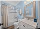 Well-lit bathroom with blue walls, a white vanity, and a bathtub/shower combo at 310 E Waterlynn Rd, Mooresville, NC 28115