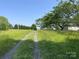 Gravel driveway surrounded by tall grass and lush trees under a clear blue sky at 3103 Blue Ridge Dr, Shelby, NC 28150