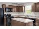 A kitchen with a center island, brown cabinets, stainless steel sink, and black appliances at 336 Maplestead St # 1080, Lancaster, SC 29720