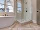 This bright bathroom has a white freestanding tub under a window next to a glass shower at 3439 Stags Leap Way, York, SC 29745