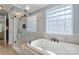 Modern bathroom features a glass-enclosed shower, a separate soaking tub, and a window allowing natural light to fill the space at 3909 Black Sycamore Dr, Charlotte, NC 28226