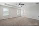Bright, spacious bedroom featuring a tray ceiling, ceiling fan, and dual windows at 392 Winecoff Woods Nw Dr, Concord, NC 28027