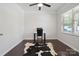 A room featuring hard wood floors, a modern ceiling fan, a large window, and neutral paint, styled with a desk and cowhide rug at 392 Winecoff Woods Nw Dr, Concord, NC 28027