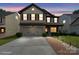Charming two-story home featuring a two-car garage, neutral siding and manicured landscaping, under a beautiful sunset sky at 392 Winecoff Woods Nw Dr, Concord, NC 28027