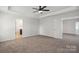 Spacious main bedroom with neutral carpet, tray ceiling, ceiling fan, and ensuite bathroom access at 392 Winecoff Woods Nw Dr, Concord, NC 28027