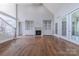 Bright living room featuring a fireplace with built-in shelving, hardwood floors and access to outside through French doors at 4113 Hoffmeister Dr, Waxhaw, NC 28173