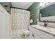 Bathroom features a shower with floral curtain, a white vanity, and modern dark green walls at 5359 Lake Glenn Dr, Stanfield, NC 28163