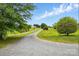 Long gravel driveway leading to a beautiful house with a spacious front yard and mature trees at 5359 Lake Glenn Dr, Stanfield, NC 28163
