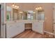 A bathroom with wood floors, double sinks, and plenty of storage with mirrors covering the vanity area at 5607 Fulton Ridge Dr, Indian Trail, NC 28079
