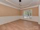 Elegant dining room featuring modern light fixture, neutral walls, wainscoting and light-colored wood flooring at 5607 Fulton Ridge Dr, Indian Trail, NC 28079