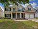 Charming two-story home featuring a brick facade, tan siding, well-kept lawn, and an attached two-car garage at 5607 Fulton Ridge Dr, Indian Trail, NC 28079