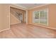 An inviting living room features a staircase, large window, neutral walls, and light-colored wood flooring at 5607 Fulton Ridge Dr, Indian Trail, NC 28079
