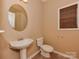 A well-lit powder room features a pedestal sink, a round mirror and a toilet at 5607 Fulton Ridge Dr, Indian Trail, NC 28079