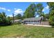 The backyard features a well-manicured lawn, mature trees, a concrete patio, and neutral-colored siding at 6406 Old Meadow Rd, Charlotte, NC 28227