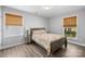 This cozy bedroom features wood floors, warm lighting, and bright windows covered with woven shades at 6406 Old Meadow Rd, Charlotte, NC 28227