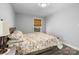 This bedroom features a comfortable bed, wood floors, warm lighting, and a bright window with woven shades at 6406 Old Meadow Rd, Charlotte, NC 28227