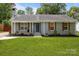 Charming one-story home with a beautifully landscaped front yard and gray brick exterior at 6406 Old Meadow Rd, Charlotte, NC 28227