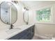Bathroom vanity features double sinks with dark cabinets, quartz countertop and two oval mirrors at 6641 Pawnee Dr, Charlotte, NC 28214