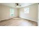 A bright, neutral bedroom with wood flooring, a ceiling fan, and two windows providing natural light at 6641 Pawnee Dr, Charlotte, NC 28214
