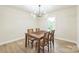 A simple dining room with a wood table, chairs, light fixture and a view from the large window at 6641 Pawnee Dr, Charlotte, NC 28214