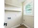 A basic laundry room with floating shelves, connections for washer/dryer, and a window for natural light at 6641 Pawnee Dr, Charlotte, NC 28214