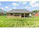 A well-manicured lawn complements a brick home featuring a covered patio great for outdoor relaxation and entertainment at 8840 Mullis Forest Ct, Mint Hill, NC 28227