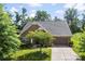 Well-maintained brick home with a lush lawn, mature trees, and an attached two-car garage at 8840 Mullis Forest Ct, Mint Hill, NC 28227