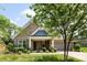 Charming brick home features a manicured lawn, lush landscaping, blue shutters, and inviting front porch at 8840 Mullis Forest Ct, Mint Hill, NC 28227