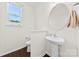 Well lit powder room with pedestal sink, decorative mirror, and window at 8840 Mullis Forest Ct, Mint Hill, NC 28227