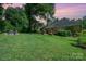 Spacious backyard with lush lawn, patio, and mature trees creating a private oasis at sunset at 105 Banksridge Rd, Fort Mill, SC 29715