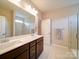 Bathroom with double vanity, dark cabinets, towel racks, large mirror, tile floors, and a glass door shower at 114 Sierra Chase Dr, Statesville, NC 28677