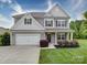 Charming two-story home with gray siding, shutters, landscaped yard, a two-car garage, and covered front porch at 114 Sierra Chase Dr, Statesville, NC 28677