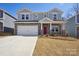 Charming two-story home featuring a stone facade, white garage door, and a vibrant red front door at 116 Obadiah Ct, Mooresville, NC 28115
