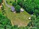 Lovely aerial image shows a house surrounded by green foliage and open green space with a storage building nearby at 11850 Sugar Hill Rd, Davidson, NC 28036